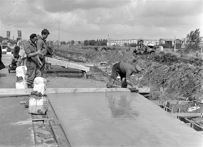 Een kruising in de Tiendweg wordt verbeterd. Beton is gestort in de bekisting voor het wegdek.