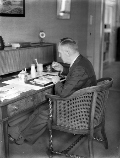 Ir. L.T. van der Wal luncht in zijn werkkamer. Van der Wal was directeur-hoofdingenieur van de Provinciale Waterstaat en directeur van de Provinciale Planologische Dienst in Zuid-Holland. De foto is waarschijnlijk gemaakt tussen 1946 en 1952.