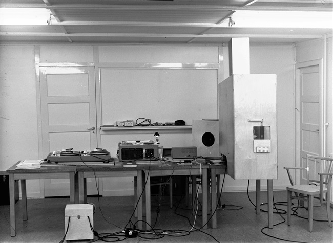 De Fotografische afdeling van de provincie Zuid-Holland in een gebouw aan de Riouwstraat. Met deze apparatuur wordt geluid op een filmband gezet. De foto is gemaakt rond 1960.