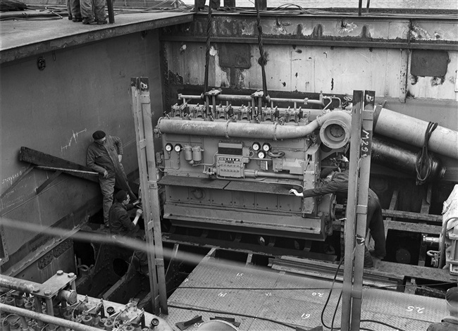 Monteurs plaatsen een machine in de veerboot Haringvliet. De Haringvliet onderhield de veerverbinding tussen Hellevoetsluis en Middelharnis.