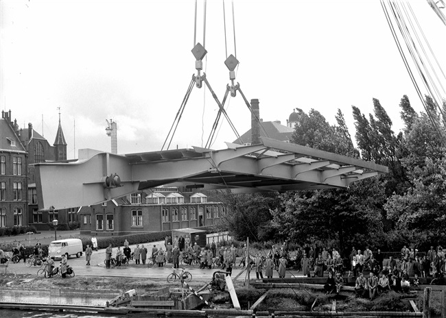 De bovenbouw van de eerste St. Sebastiaansbrug wordt geplaatst. Op de achtergrond het voormalige laboratorium van de Afdeling Physica en Electrotechniek van de Polytechnische School.