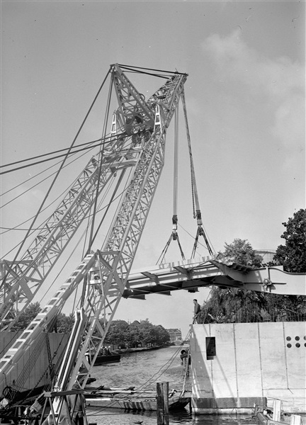 Een drijvende bok plaatst de bovenbouw van de eerste St. Sebastiaansbrug, over het Rijn-Schiekanaal.