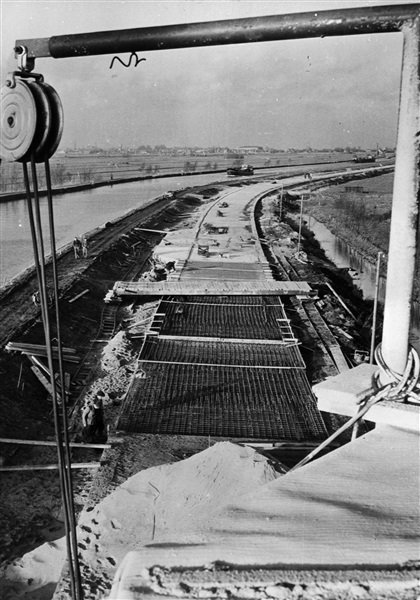 Aanleg van de weg op palen tussen Boskoop en Alphen aan den Rijn. Vanaf een verrijdbare vlonder wordt het beton in de bekisting gestort.