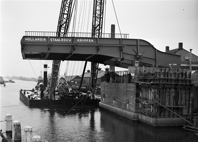 Een drijvende bok plaatst de bovenbouw van de 's-Molenaarsbrug op het brughoofd.