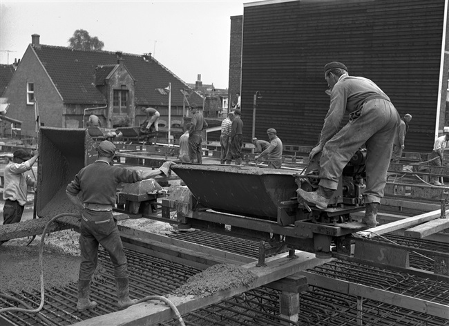 Betontimmermannen storten beton in de bekisting voor het noordelijke viaduct. Het viaduct is onderdeel van de eerste St. Sebastiaansbrug.