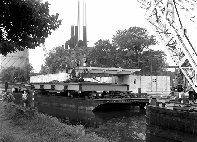 Een drijvende bok plaatst de bovenbouw van de eerste St. Sebastiaansbrug. De basculebrug over het Rijn-Schiekanaal verbindt de oude binnenstad van Delft met de TU-wijk. Op de achtergrond de gasfabriek, die later is gesloopt.