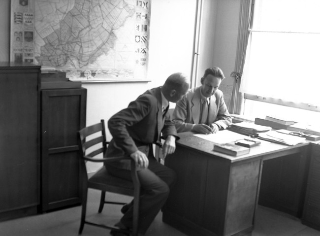 Ambtenaren van Provinciale Waterstaat in hun kantoor. De foto is waarschijnlijk gemaakt tussen 1950 en 1952.