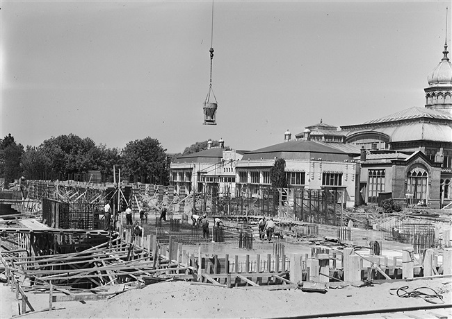 Beton wordt gestort in de bekisting voor het souterrain van het provinciehuis, dat in aanbouw is. Op de achtergrond het Moorse Paleis (hoofdgebouw) van de voormalige Haagsche Dierentuin, dat eind 1968 is gesloopt.