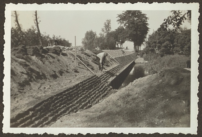 Werker legt stapelzoden langs de oever in Hoogmade, 1933