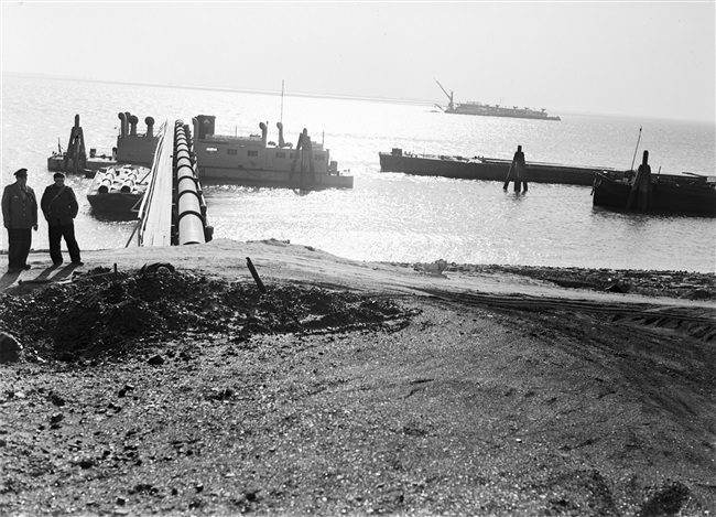De dijk bij de Hoek van Sint Jacob op Goeree-Overflakkee wordt hersteld na de watersnoodramp van 1 februari 1953. Zand en water worden via een buis geperst naar de plek waar een nieuw dijklichaam wordt opgespoten.