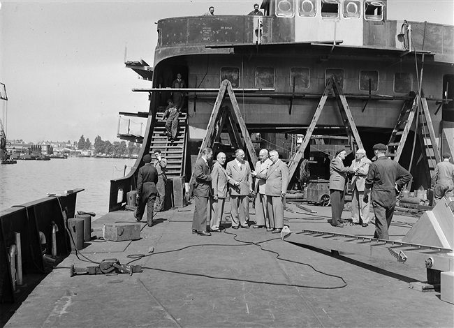 Gedeputeerde A.C.A. Deerenberg (rechts in de groep) bezichtigt de veerboot Haringvliet, die een volledige nieuwe opbouw krijgt.