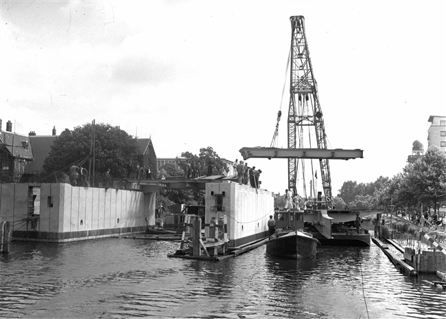 Een drijvende bok plaatst de bovenbouw van de eerste St. Sebastiaansbrug over het Rijn-Schiekanaal.