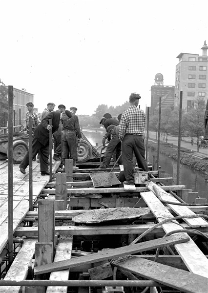 Beton wordt gestort in de bekisting voor de middenpijler van de eerste St. Sebastiaansbrug, over het Rijn-Schiekanaal.