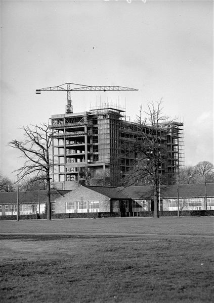 Het betonskelet van de hoogbouw van het nieuwe provinciehuis, gezien vanaf het Malieveld. Op de voorgrond vermoedelijk de noodgebouwen van Rijkswaterstaat.
