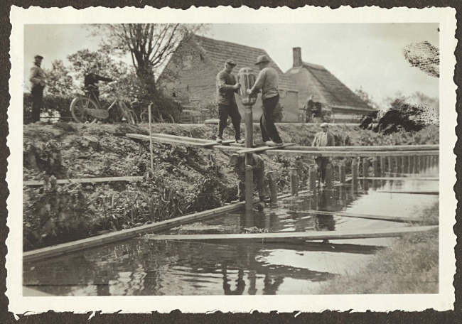 Werkers slaan palen voor oeverbescherming in Hoogmade, 1933