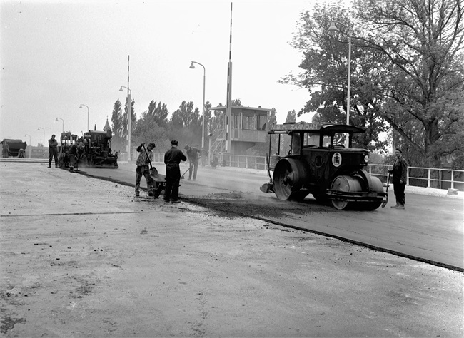 Asfaltafwerkers brengen de asfalt wegverharding aan op de eerste St. Sebastiaansbrug.