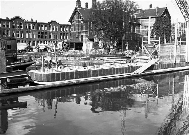Bouw van de middenpijler van de eerste St. Sebastiaansbrug over het Rijn-Schiekanaal. Op de achtergrond het voormalige microbiologielaboratorium van de Polytechnische School.