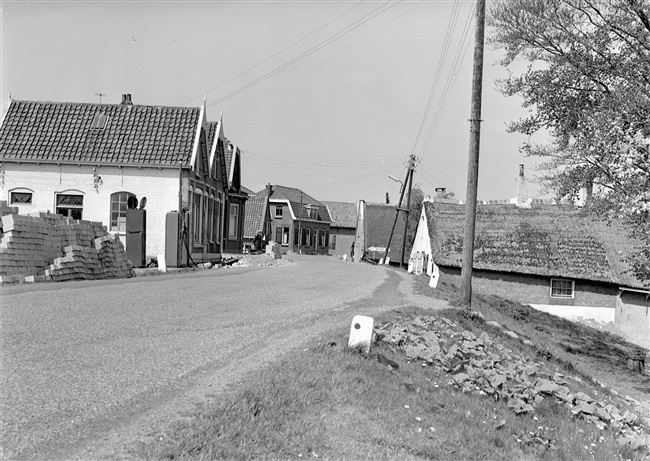 Een verhoogde dijk met woningen, waarvan er enkele gevijzeld zullen worden, oftewel omhoog gebracht.