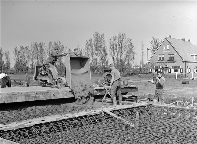 Aanleg van de weg op palen tussen Boskoop en Alphen aan den Rijn. Vanaf een verrijdbare vlonder wordt beton gestort in de wapening voor het wegdek.