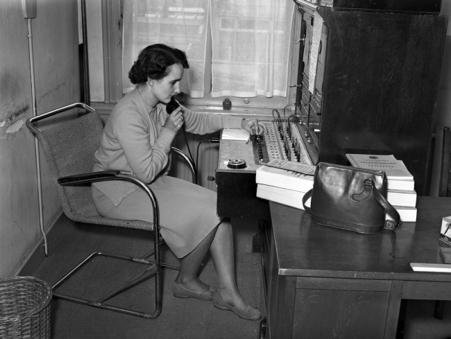 Een telefoniste bedient de telefooncentrale in het provinciehuis. De foto is waarschijnlijk gemaakt tussen 1950 en 1952.