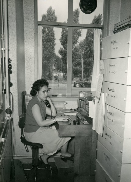 Een telefoniste in dienst van de provincie Zuid-Holland bedient een telefooncentrale. Dit kantoor aan het Korte Voorhout 9 is bij een bombardement op 3 maart 1945 verwoest. Deze foto is gemaakt tussen 1930 en 1944.