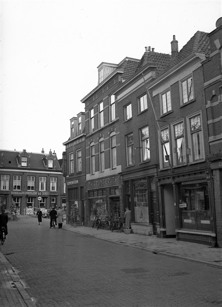 De Choorstraat in Delft. Op de hoek van Leeuwenstein Naaimachines met ernaast P. de Gruyter en Zn. Links Vrouwjuttenland met de Boek en Handelsdrukkerij. De foto is waarschijnlijk gemaakt tussen 1946 en 1952.