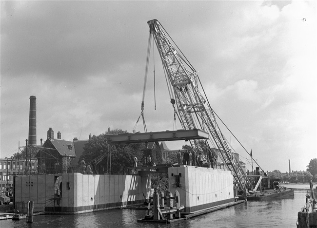 Een drijvende bok plaatst de bovenbouw van de eerste St. Sebastiaansbrug, over het Rijn-Schiekanaal.