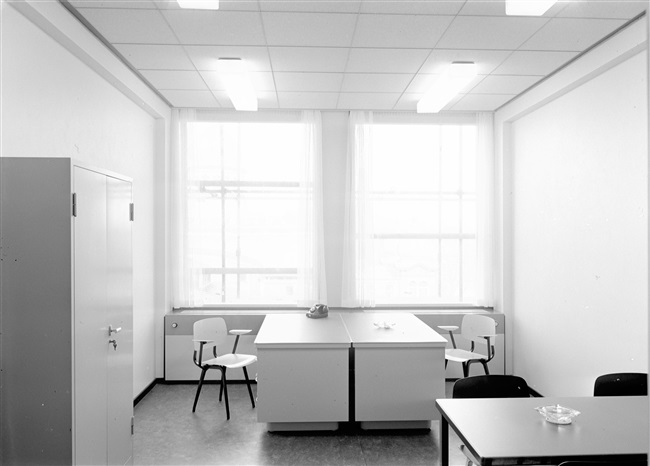 Modelkamer voor twee ambtenaren, voor het nieuwe provinciehuis. In de kamer staan twee bureaus met twee stoelen (firma Ahrend) en een vergadertafel. Op 21 mei 1964 werd het nieuwe provinciehuis geopend.