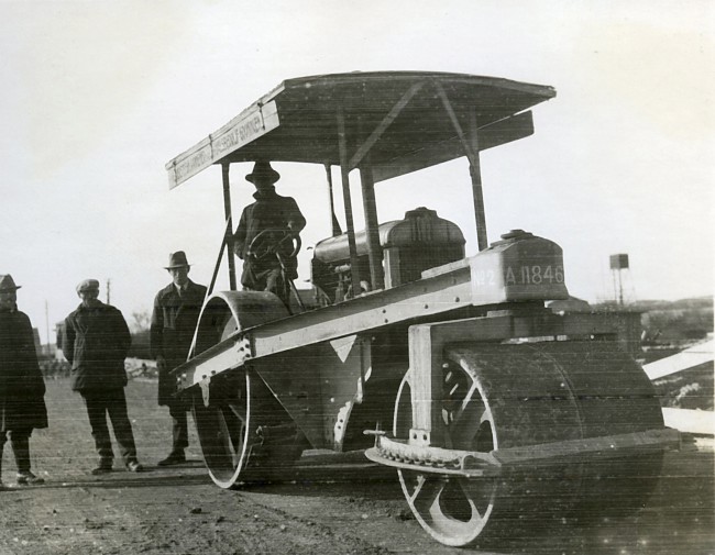 Een wegenwals wordt gebruikt bij een wegaanleg. De foto is gemaakt tussen 1920 en 1940.