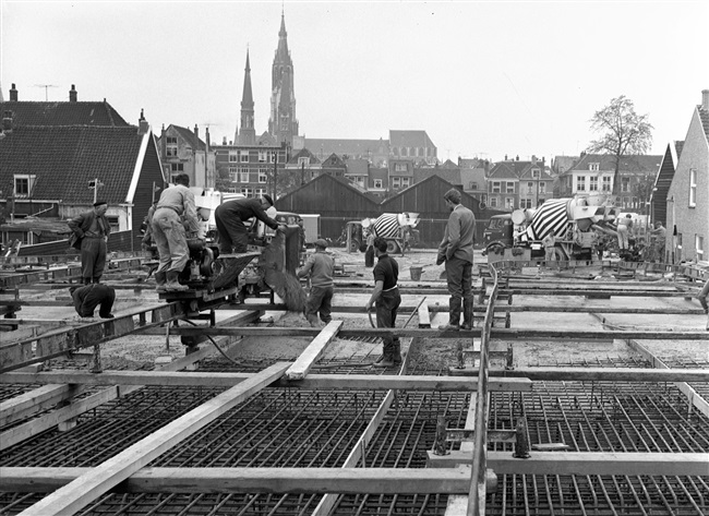 Betontimmermannen storten beton in de bekisting voor het noordelijke viaduct. Het viaduct is onderdeel van de eerste St. Sebastiaansbrug.