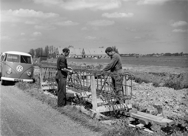 Aanleg van de weg op palen tussen Boskoop en Alphen aan den Rijn. IJzervlechters vlechten de wapening voor de dwarsbalken, waarop later het wegdek komt te rusten.