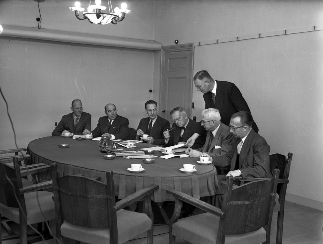 Ir. L.T. van der Wal (met pijp) vergadert met de staf. Van der Wal was directeur-hoofdingenieur van de Provinciale Waterstaat en directeur van de Provinciale Planologische Dienst. Tweede van links ir. D.M. Mathlener, adjunct-directeur-hoofdingenieur. De foto is waarschijnlijk gemaakt tussen 1950 en 1952.