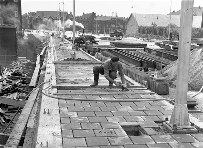 Een stratenmaker legt het trottoir aan van de in aanbouw zijnde eerste St. Sebastiaansbrug.