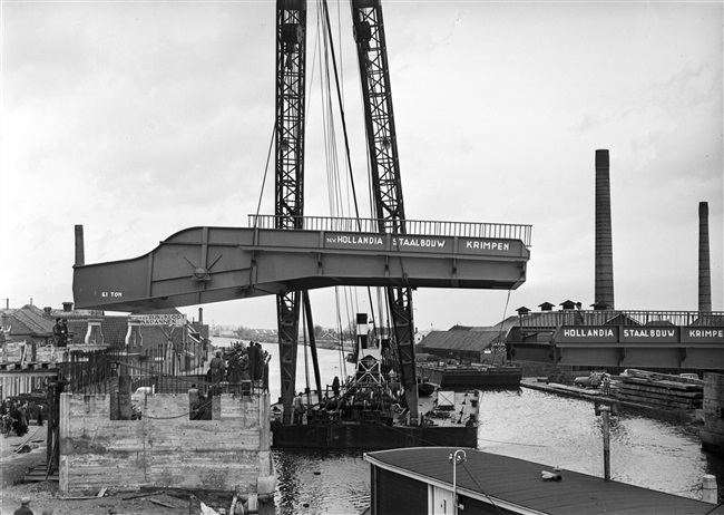 Een drijvende bok plaatst de bovenbouw van de 's-Molenaarsbrug op het brughoofd.