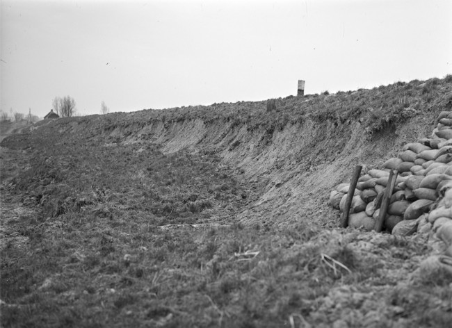 De beschadigde Zegenpoldersedijk is met zandzakken verstevigd, na een storm op 23 december 1954.