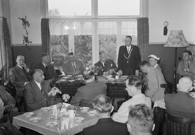 Werkbezoek van de Provinciale Staten van Zuid-Holland. Willem Timmerman, burgemeester van Meerkerk (staand) met links van hem Lodewijk Albert Kesper, commissaris van de Koningin. Bij hem aan tafel zitten ook de gedeputeerden en de griffier.