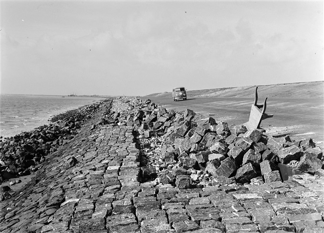 Dijkherstel in de polder Galathee (Ooltgensplaat), na de watersnoodramp van 1 februari 1953. Het nieuwe dijklichaam van opgespoten zand is bekleed met asfalt. De glooiing onderaan de dijk wordt afgewerkt met stenen.