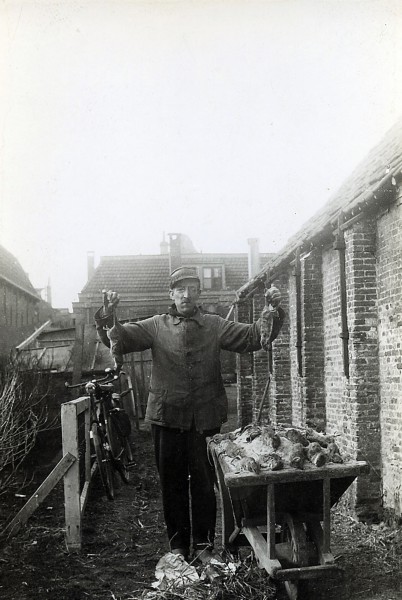 Rattenvanger. Deze man is een ambtenaar van de Provinciale Waterstaat of een inwoner die de ratten tegen betaling ving. De foto is gemaakt tussen 1920 en 1940.